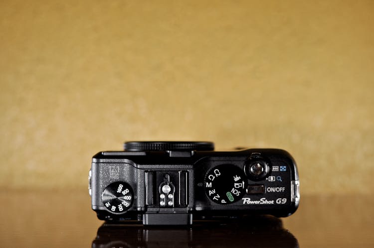 Top View Of A Digital Camera With Dials Against Beige Background