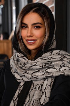 A beautiful woman with a stylish scarf, smiling warmly indoors.