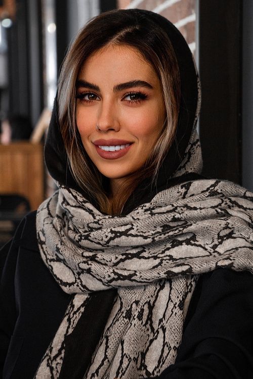 Free A beautiful woman with a stylish scarf, smiling warmly indoors. Stock Photo