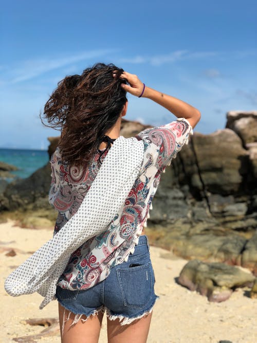 Woman Holding Her Hair Facing at Rock