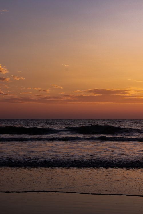 Free Stunning ocean view featuring a warm sunset and tranquil waves. Stock Photo