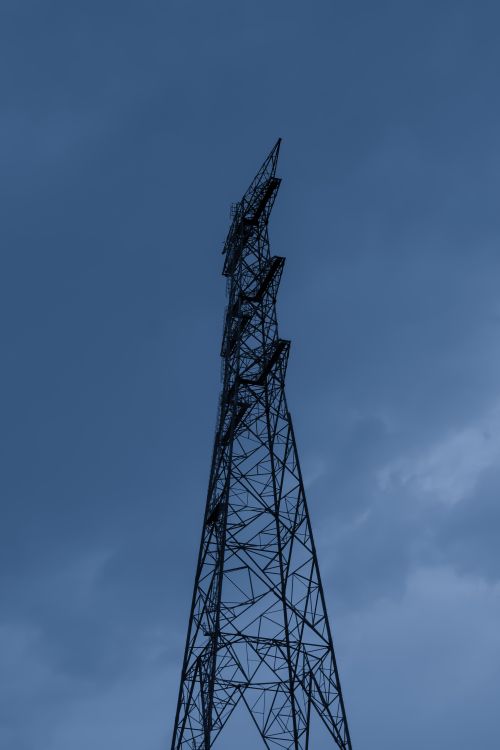 Free A low angle view of a tall electricity transmission tower set against an overcast sky. Stock Photo