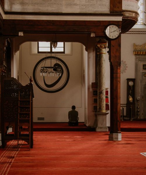 Free A person kneeling in prayer inside a beautifully adorned mosque captures a serene moment. Stock Photo