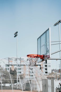 A solitary basketball hoop against a clear blue sky in an urban park, showing a sense of sport and freedom.