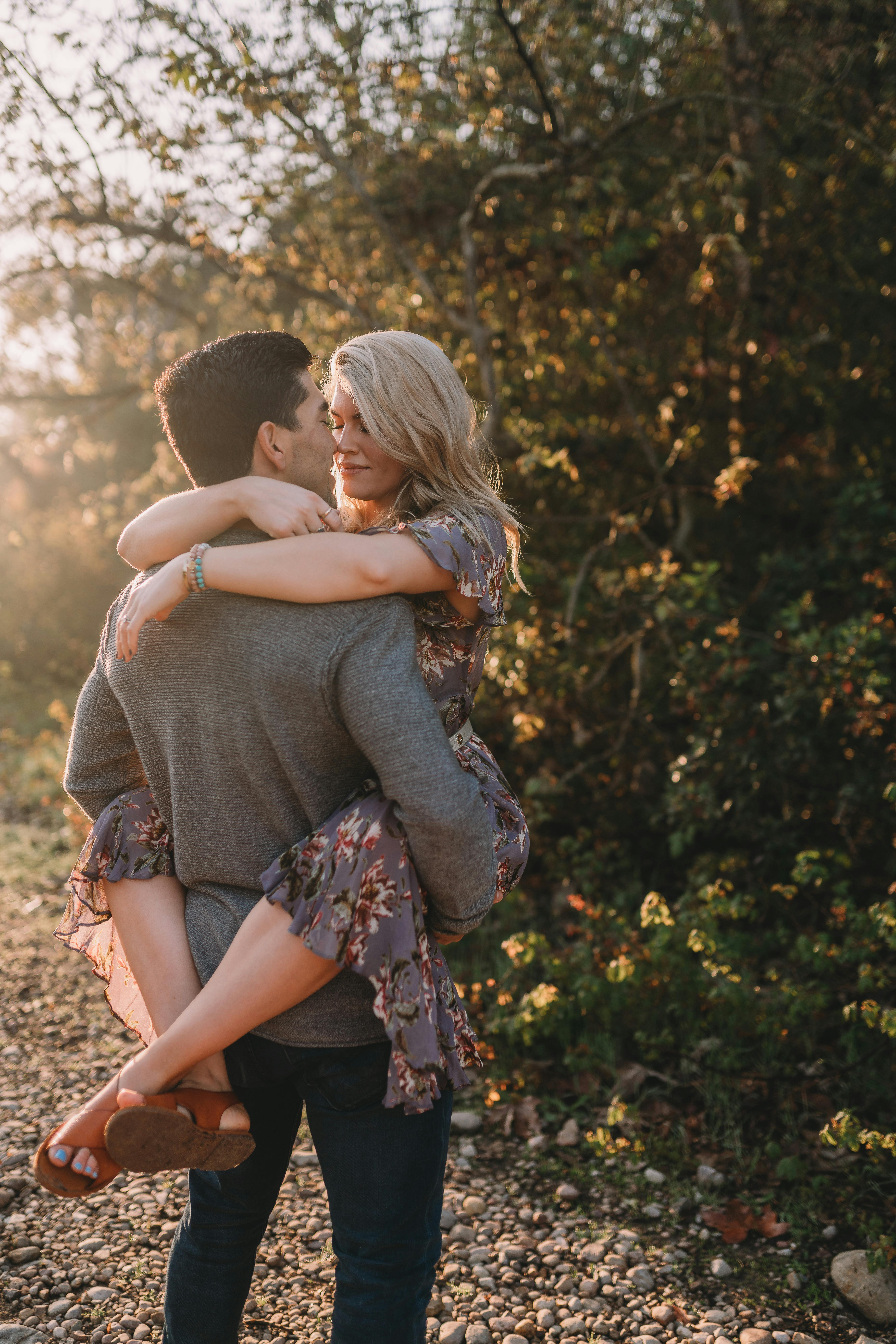 A joyful couple shares a loving embrace outdoors during sunset.