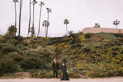 A Couple Holding Hands while Standing on the Roadside