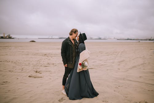 Couple Looking at Each Other Standing on Brown Sand