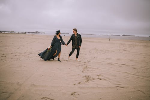 
Couple Looking at Each Other While Walking on Brown Sand