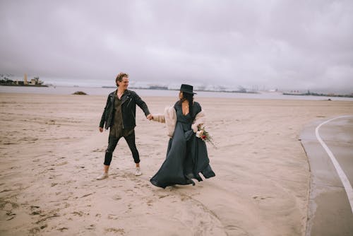 Couple Looking at Each Other While Walking on Brown Sand