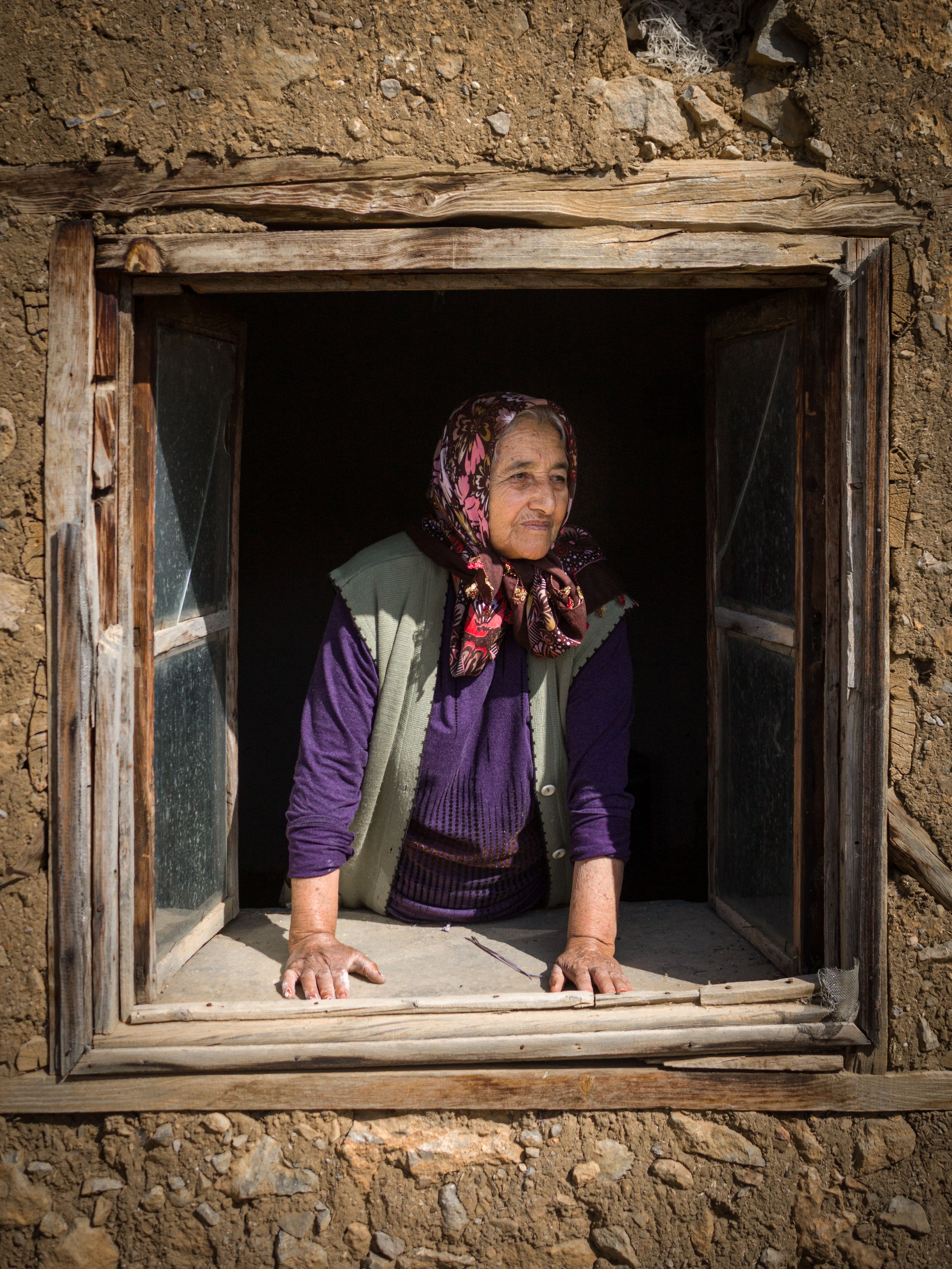 A woman standing by a window looking outside, representing solitude and the no contact period after leaving a toxic relationship
