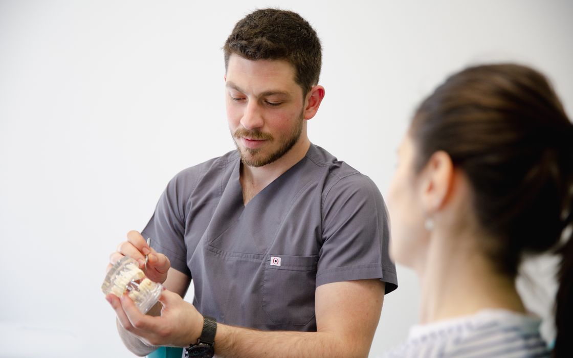Dentist holding a dental model to explain a treatment plan to a patient