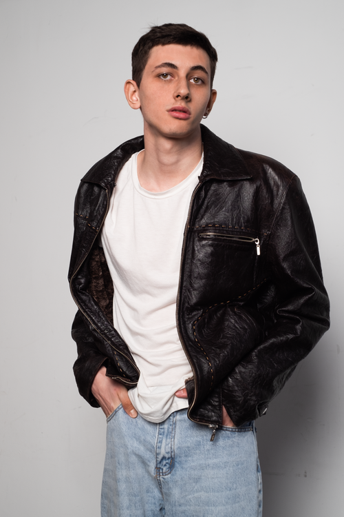 Free Stylish studio portrait of a man wearing a black leather jacket and white shirt, hands in pockets. Stock Photo