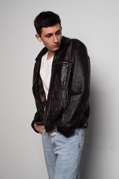 Free Portrait of a man in a black leather jacket looking over his shoulder in a studio setting. Stock Photo