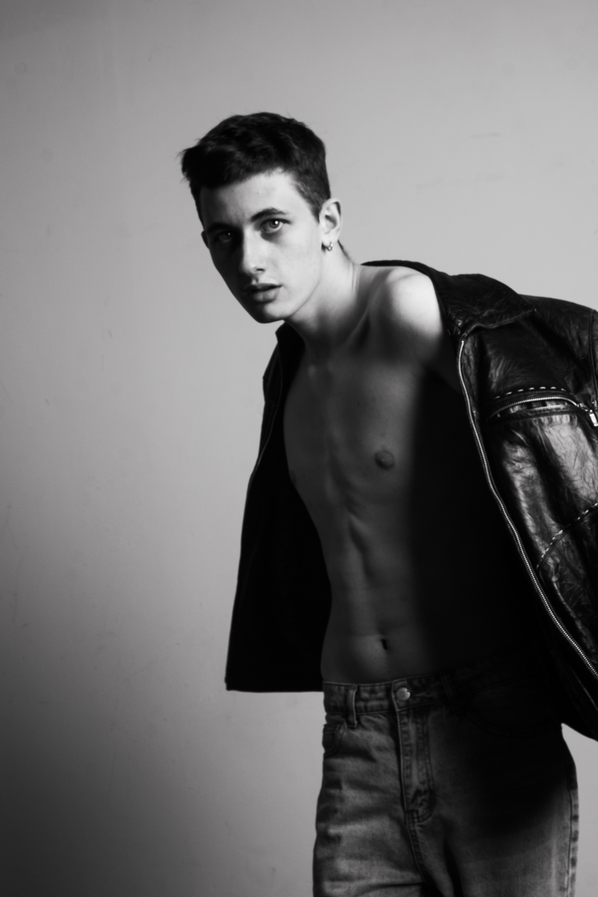 Dynamic black and white portrait of a male model in a leather jacket posing confidently.