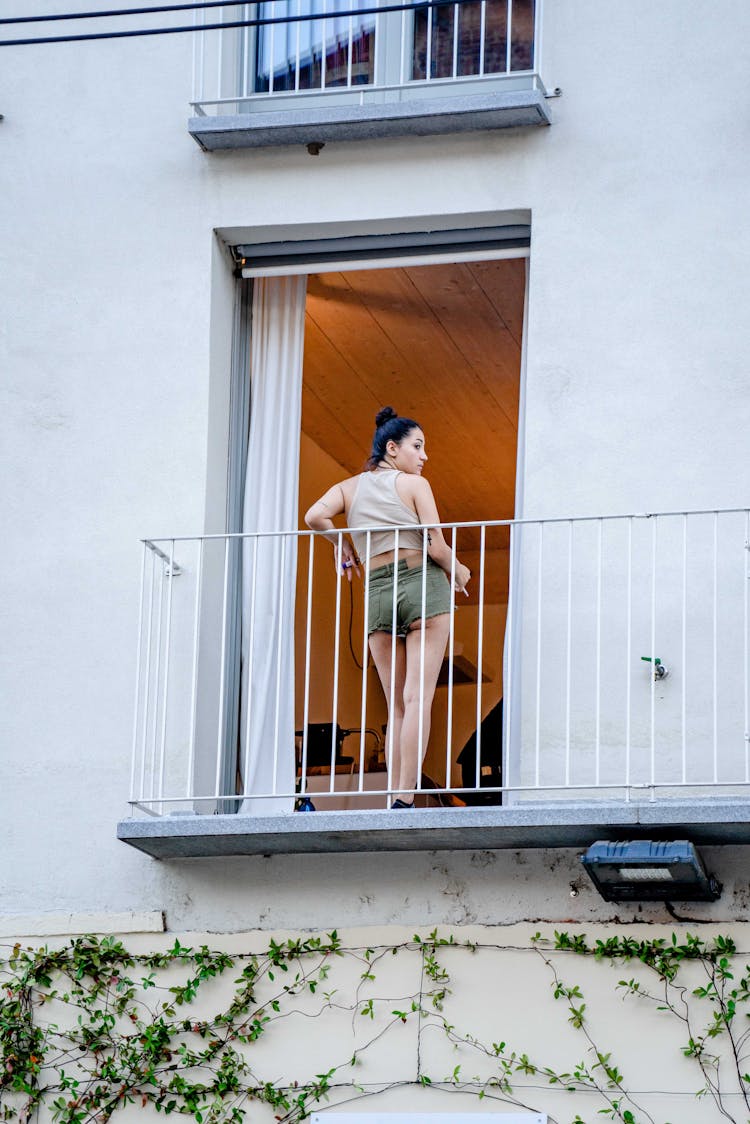 A Woman Standing At The Balcony While Looking Over Shoulder