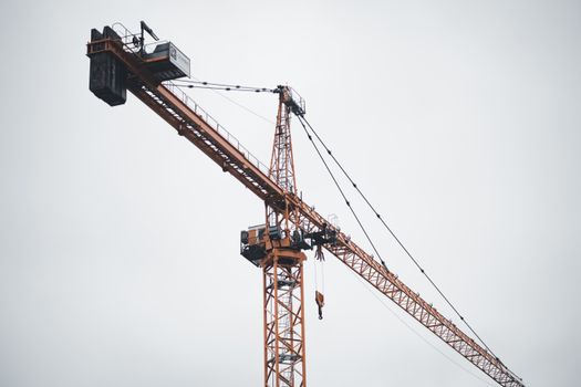 A detailed view of a tower crane against a cloudy sky, perfect for construction themes.