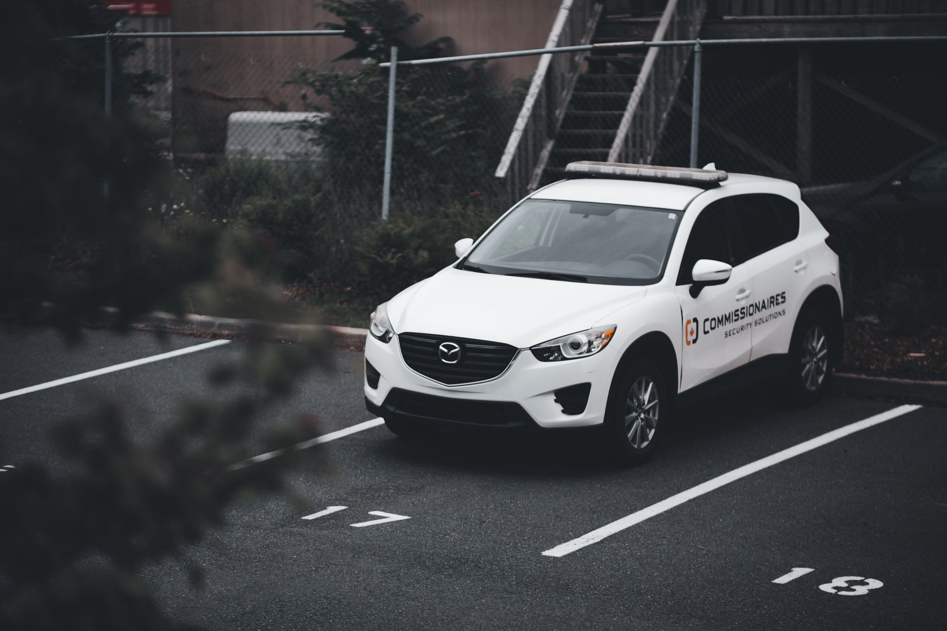 A white SUV with security branding parked in a numbered outdoor spot.
