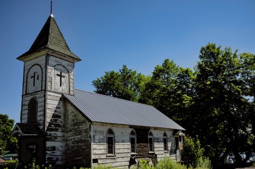 Free Old wooden chapel with weathered exterior, surrounded by trees in rural Redfield, NY. Stock Photo