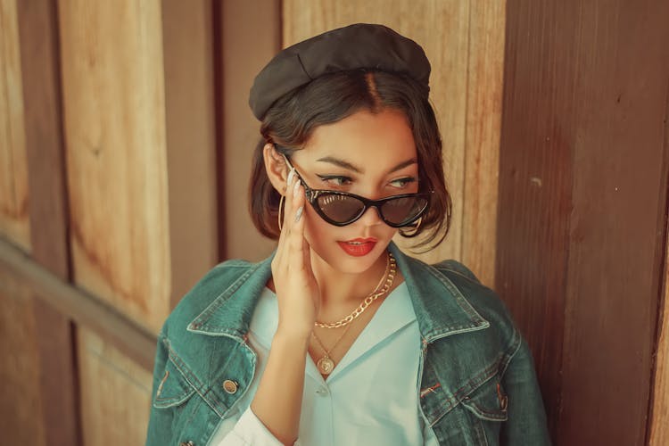 Woman Wearing A Jeans Jacket And Touching Her Sunglasses 