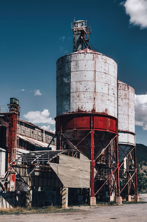 Free Old rusty silos in an industrial area with a clear blue sky backdrop. Perfect for industrial themes. Stock Photo