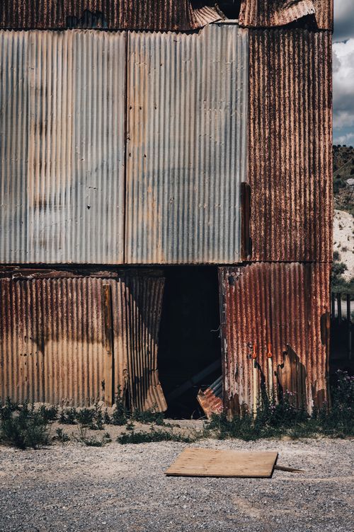 Free A weathered building facade with rusty corrugated metal, depicting decay and abandonment. Stock Photo