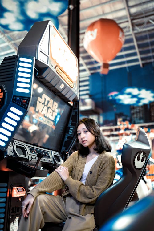 Young Woman Sitting in Game Room Before Machine