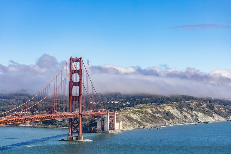 The Golden Gate Bridge under a blue sky with low cloud over the headlands — photo by Robert So on Pexels