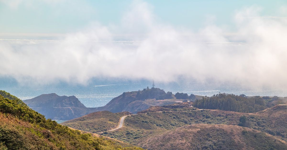 Breathtaking aerial view of coastal hills and clouds along the shore.