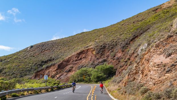 Cyclists Strolling on the Road on the Foot of the Mountain
