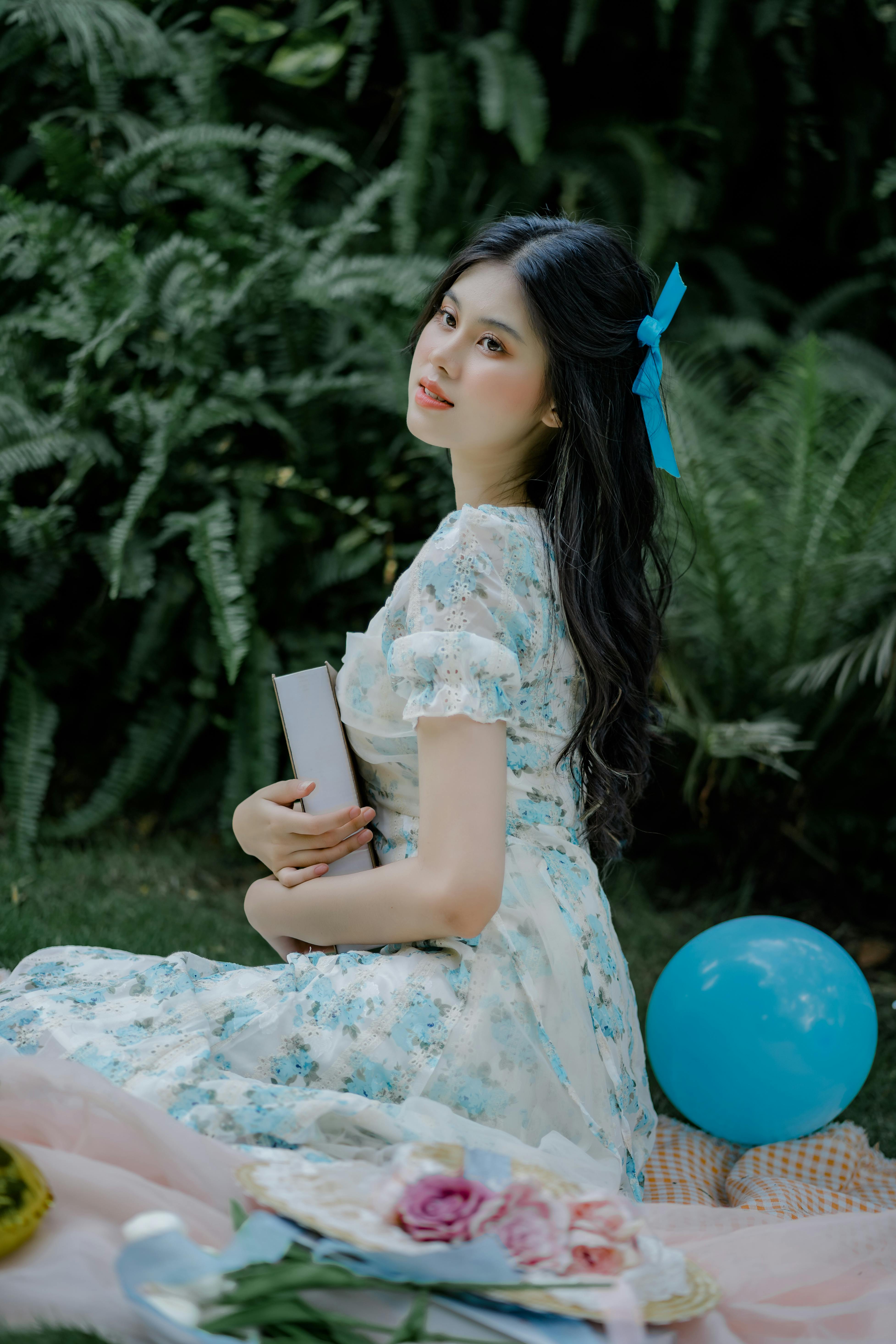 beautiful woman sitting on the blanket and holding a book