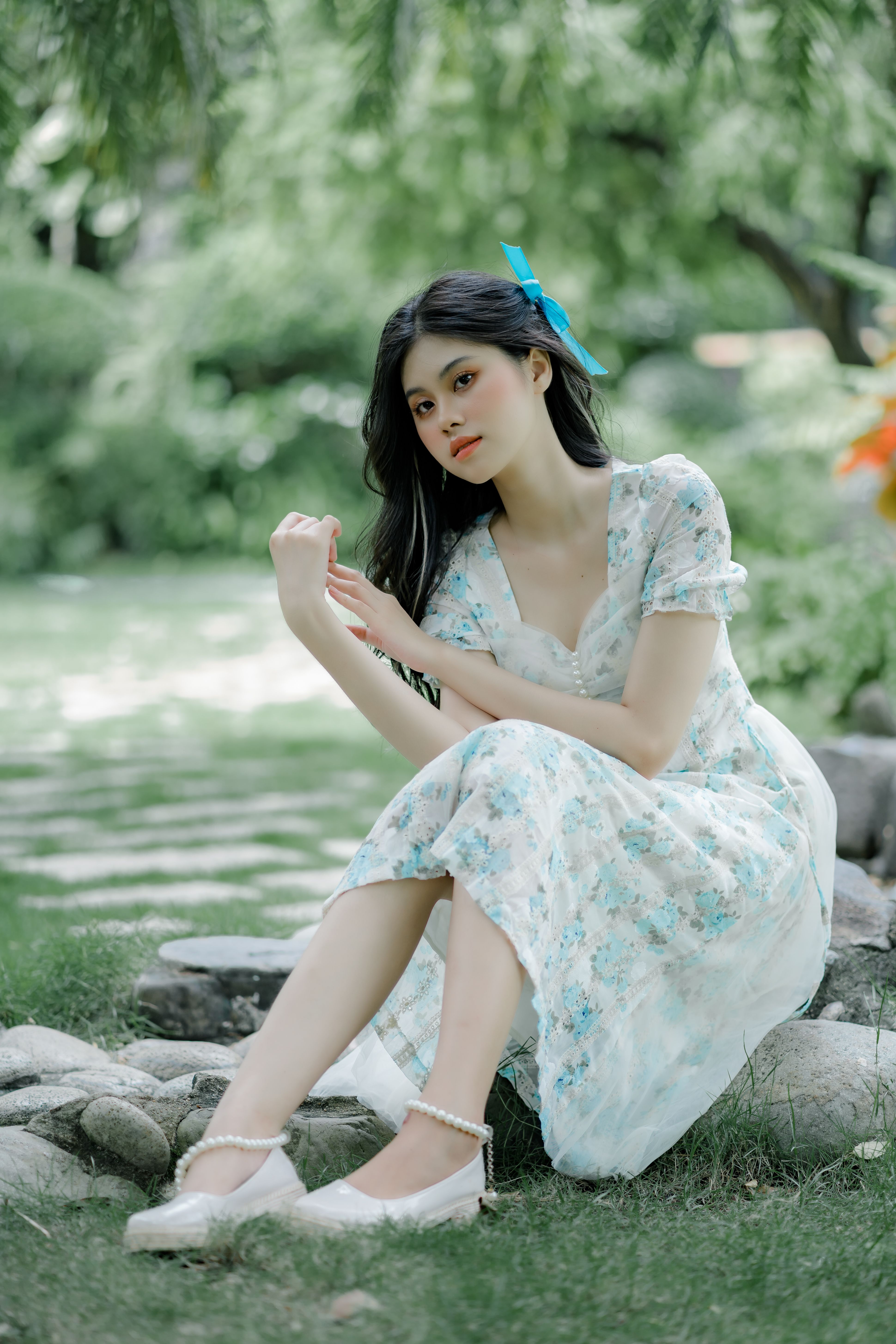 A Woman in White Floral Dress Sitting on Gray Rock · Free Stock Photo