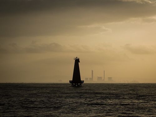Free Ethereal view of a lighthouse at sunset with industrial backdrop in Central Java. Stock Photo