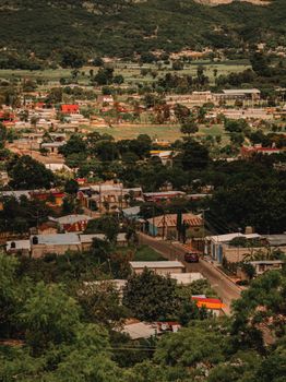 A scenic aerial view of a village with lush fields and distant hills.