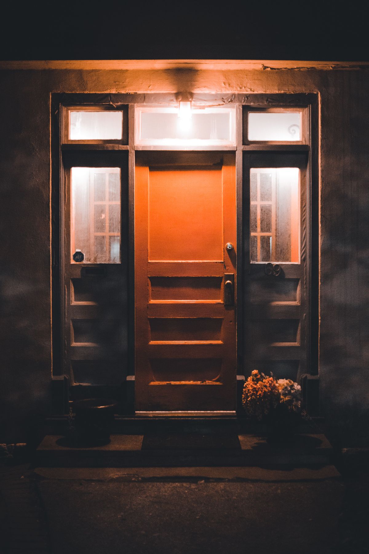 A lit front door with glass sidelights at night