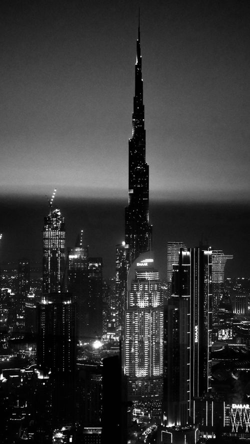 Free Dramatic black and white cityscape of Dubai featuring the iconic Burj Khalifa illuminated at night. Stock Photo