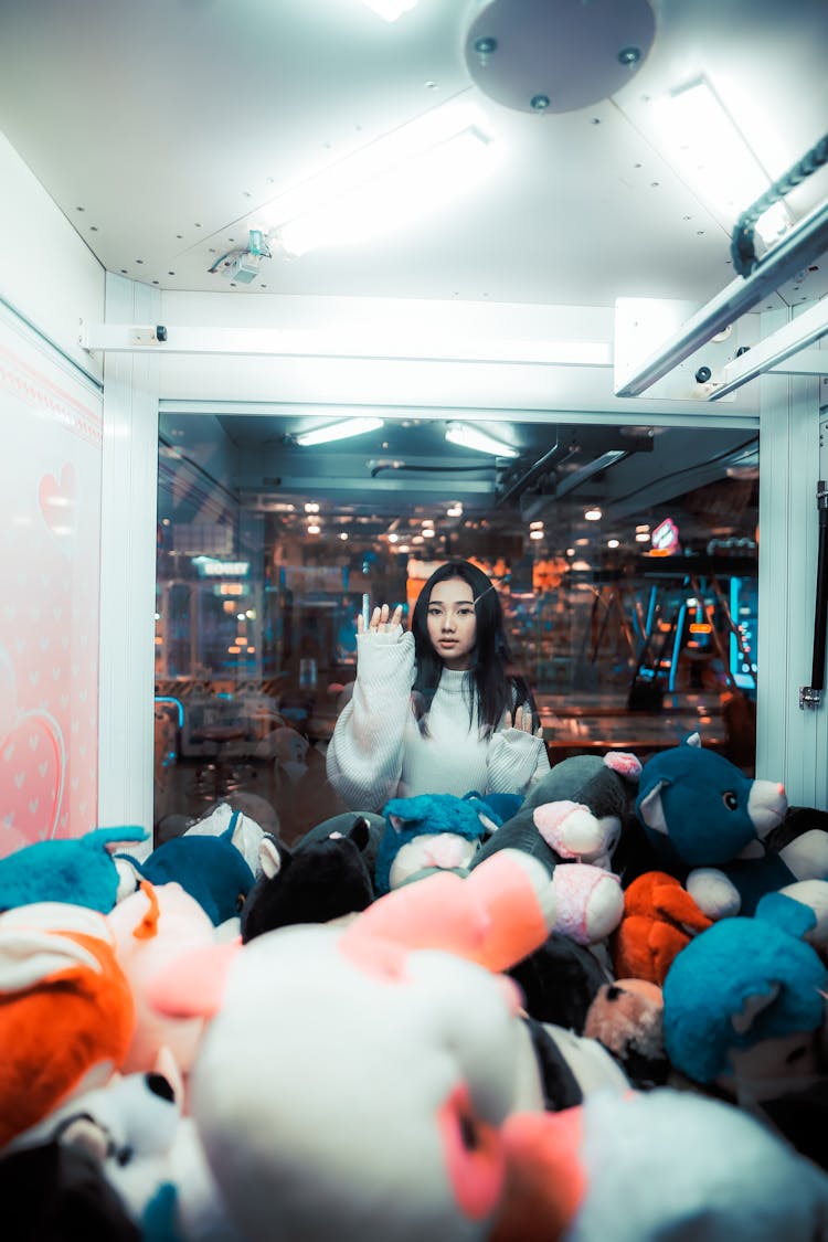 Girl Waving Hand From Behind Window In Game Room