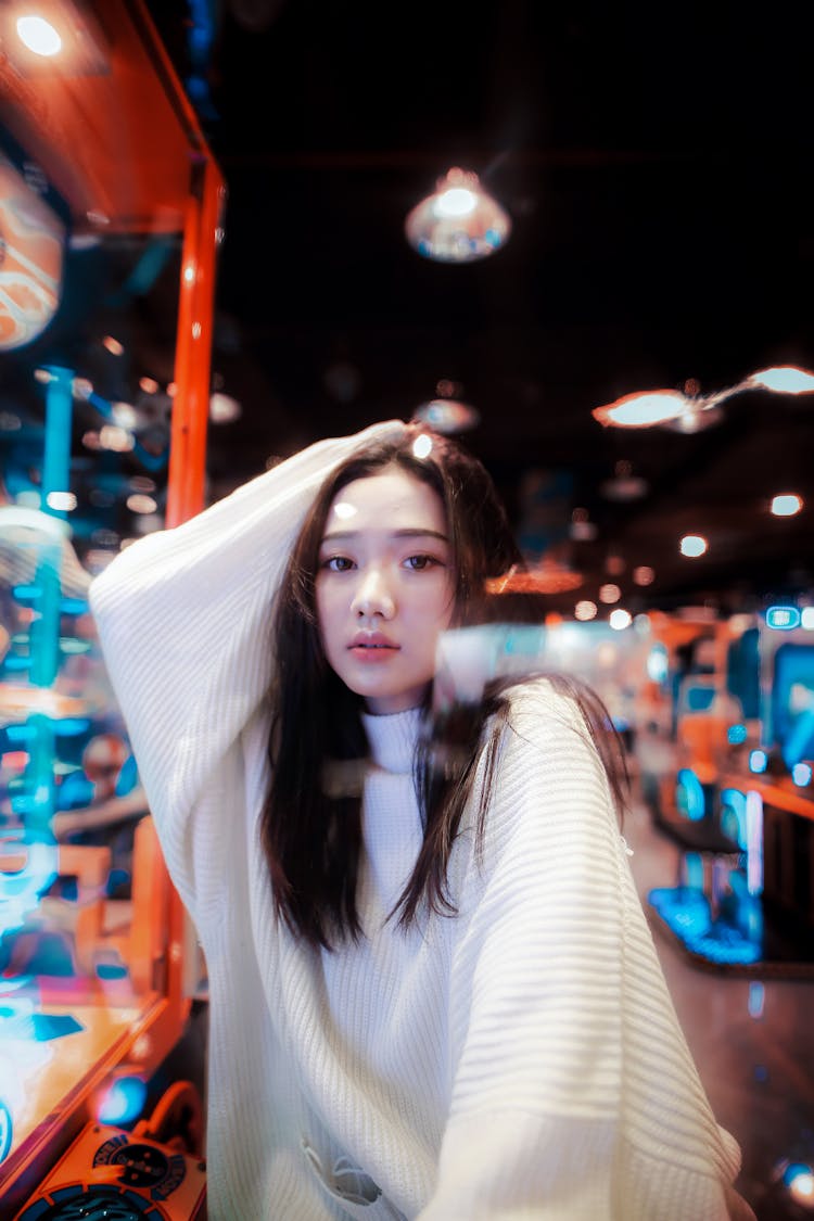 Young Woman In White Pullover Sitting Behind Glass Pane