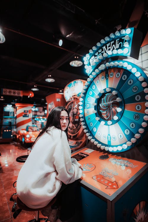 A Woman in White Long Sleeves Playing an Arcade 