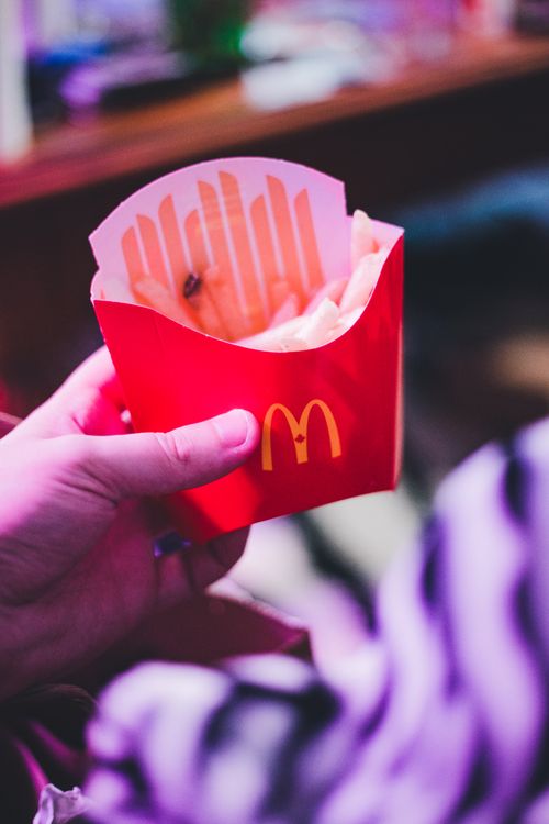 Free Hand holding a red fast-food box of french fries. Perfect for fast-food themes. Stock Photo
