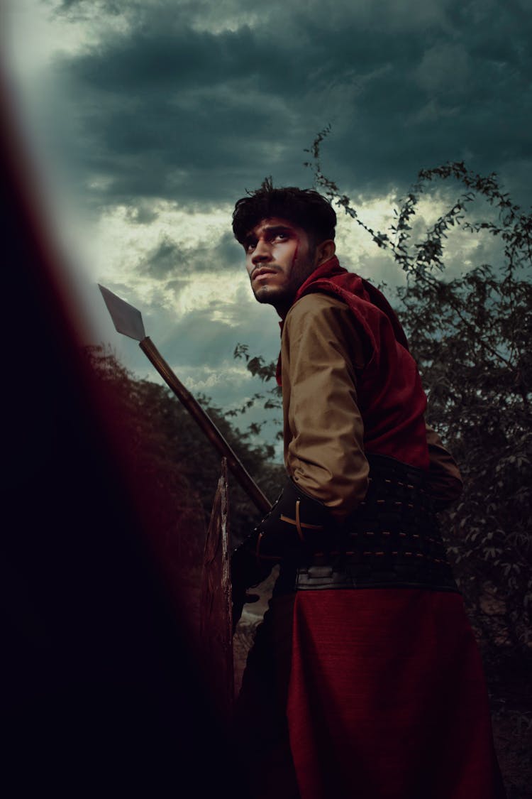 An Injured Man Holding A Spear And A Shield