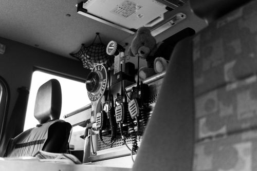 Free Black and white view inside emergency vehicle showing radios, seats, and a teddy bear. Stock Photo