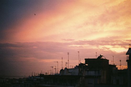 Free Silhouetted rooftops and antennas beneath a vibrant sunset sky in Thessaloniki, Greece. Stock Photo