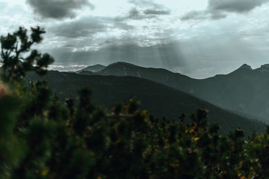 A breathtaking view of mountains with sunbeams piercing through the clouds.
