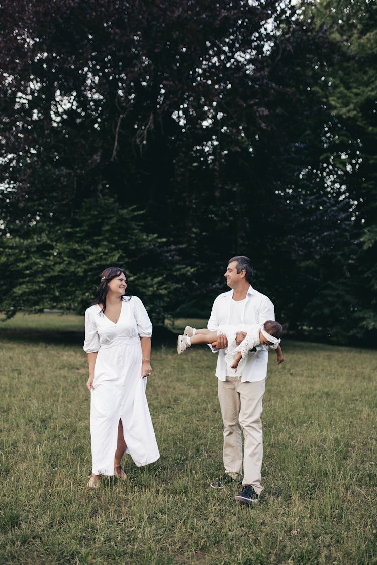 A Family Walking On Green Grass Field