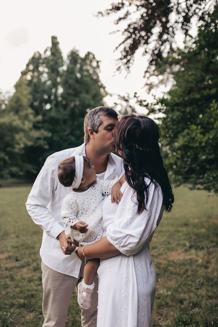 Couple Kissing And Holding A Baby 