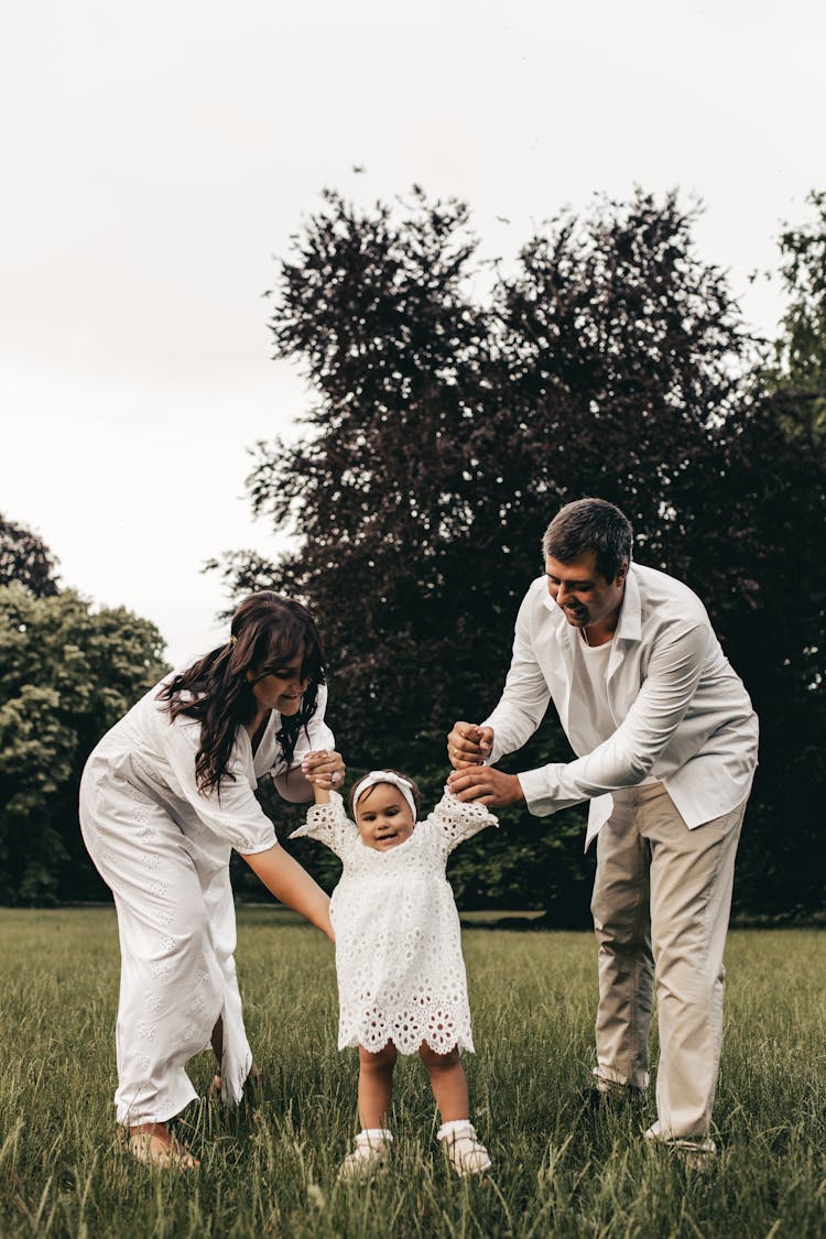 A Man And Woman Teaching A Girl To Walk