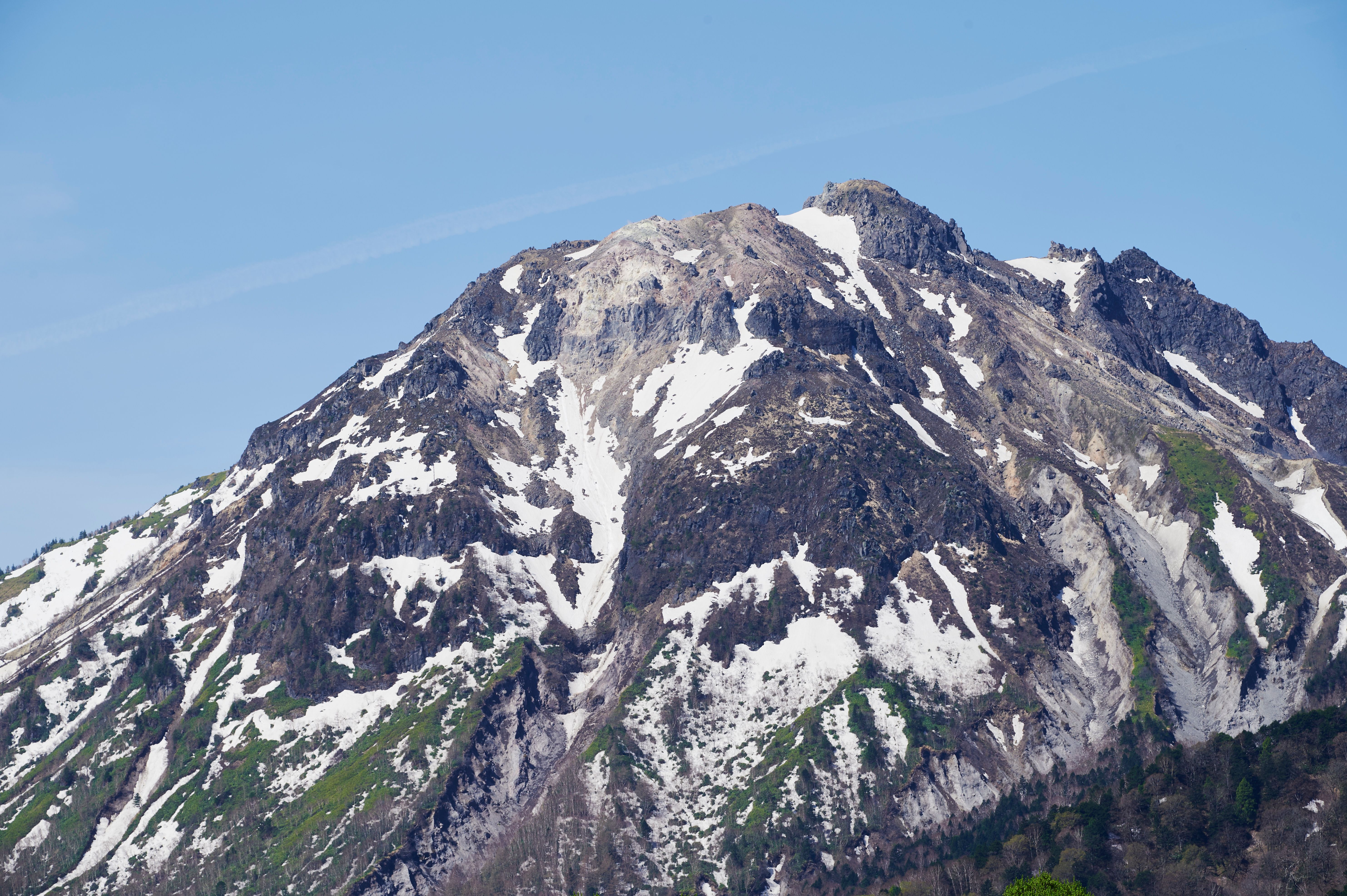 Stunning view of snow-covered Mount Norikura under a clear blue sky in Nagano, Japan.