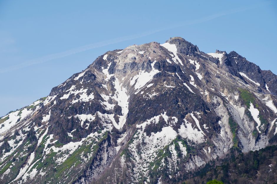 Stunning view of snow-covered Mount Norikura under a clear blue sky in Nagano, Japan.