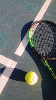 Tennis racket and ball on a sunlit court in Quận 2, Hồ Chí Minh City.