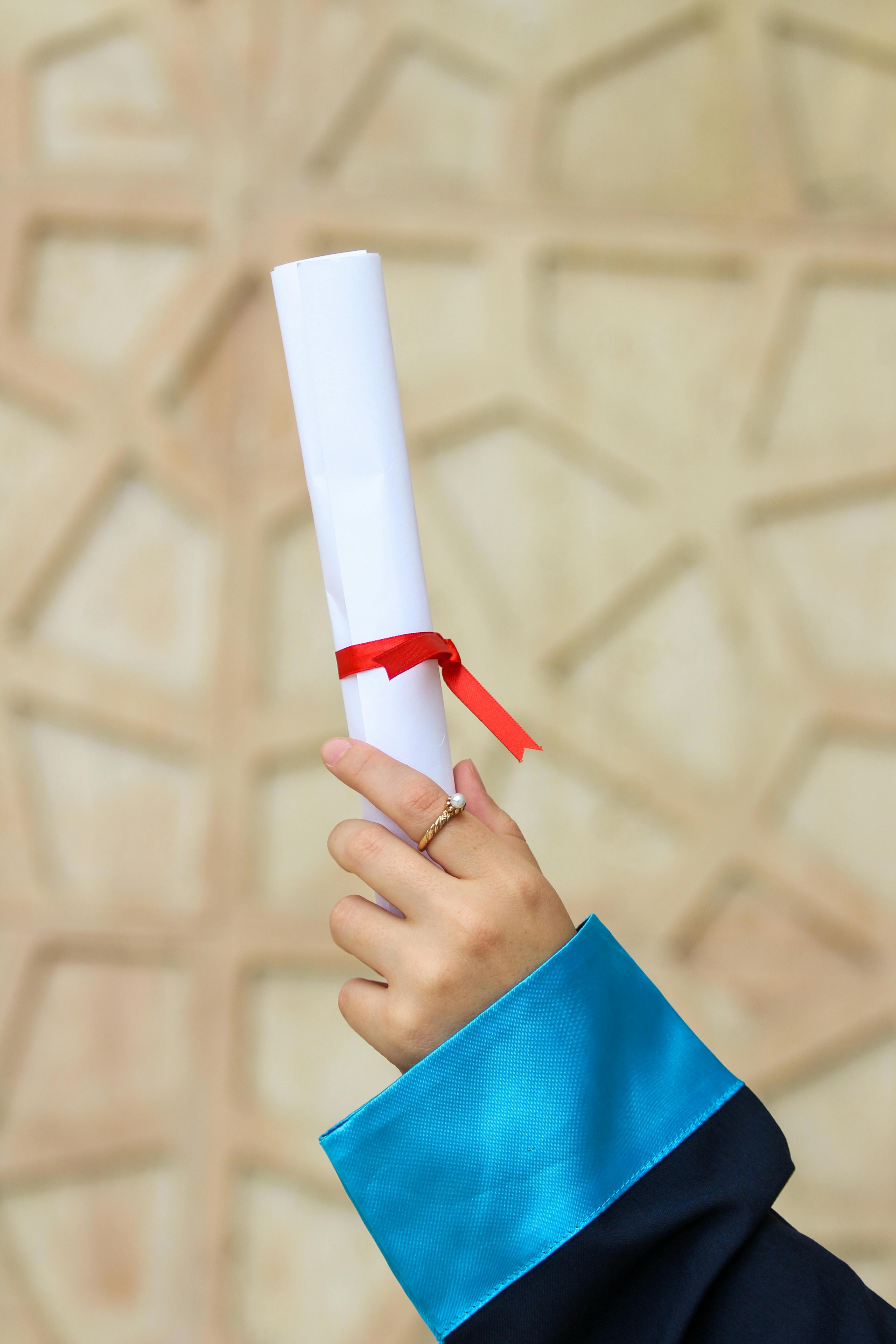 Close-up of a hand holding a diploma, symbolizing academic achievement.